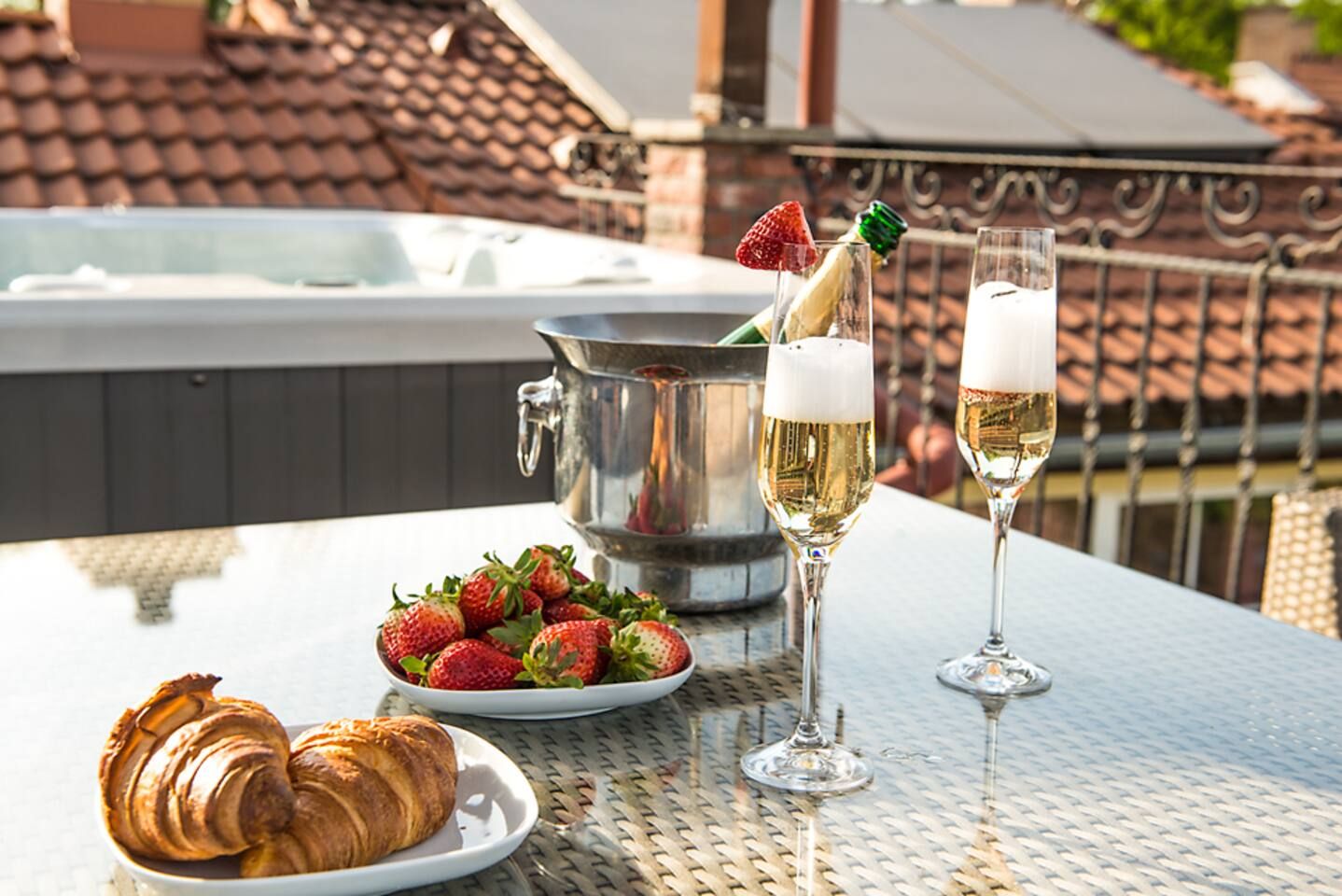 A table with croissants, strawberries, champagne glasses, and a metal bucket.