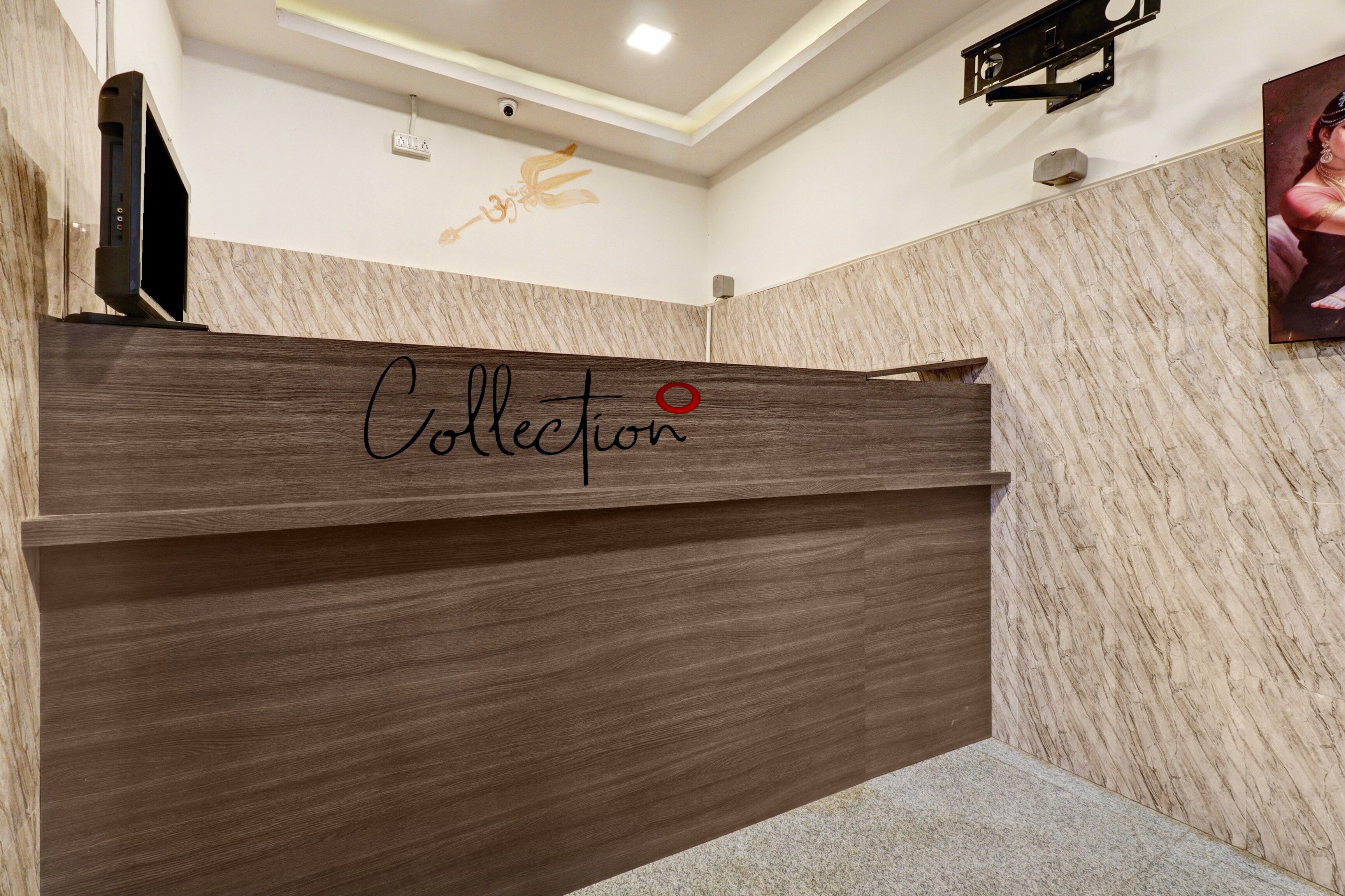 A reception desk with the word 'Collection' written on it, a security camera above, and a framed picture on the wall.