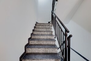 Un escalier avec une rampe en métal noir et un mur blanc.