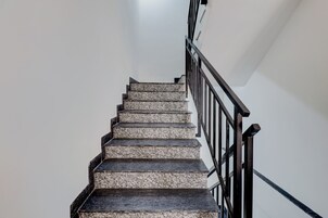 Una escalera con barandilla de metal negro y pared blanca.