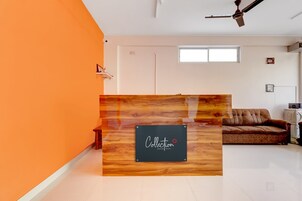 Una recepción con un cartel, un ventilador de techo, una ventana y un sofá en una habitación con una pared de acento naranja.