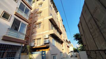 A multi-story residential building with balconies, air conditioning units, and a gated entrance.