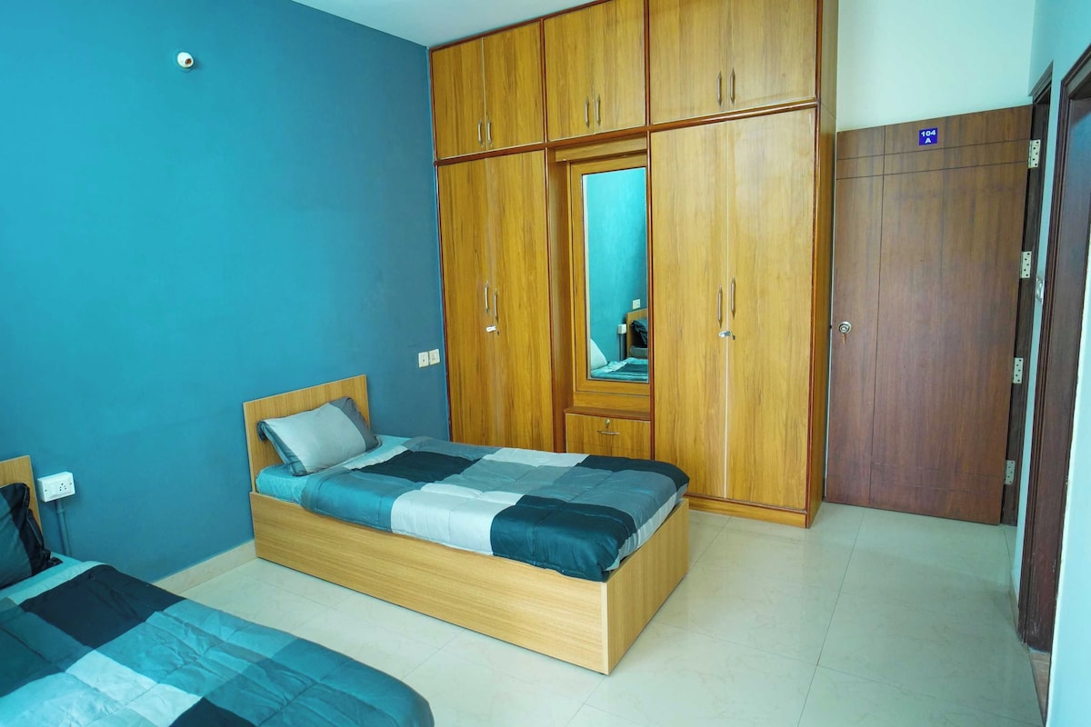 A bedroom with two beds, wooden wardrobes, and a mirror.
