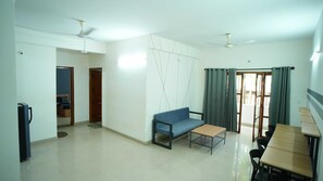 A spacious living area with a sofa, a dining table, and a ceiling fan. - Hotel O Local Square Manyata (Bangalore)