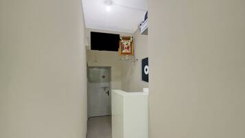 A hallway with a reception desk, a door with a number plate, and a wall-mounted television.
