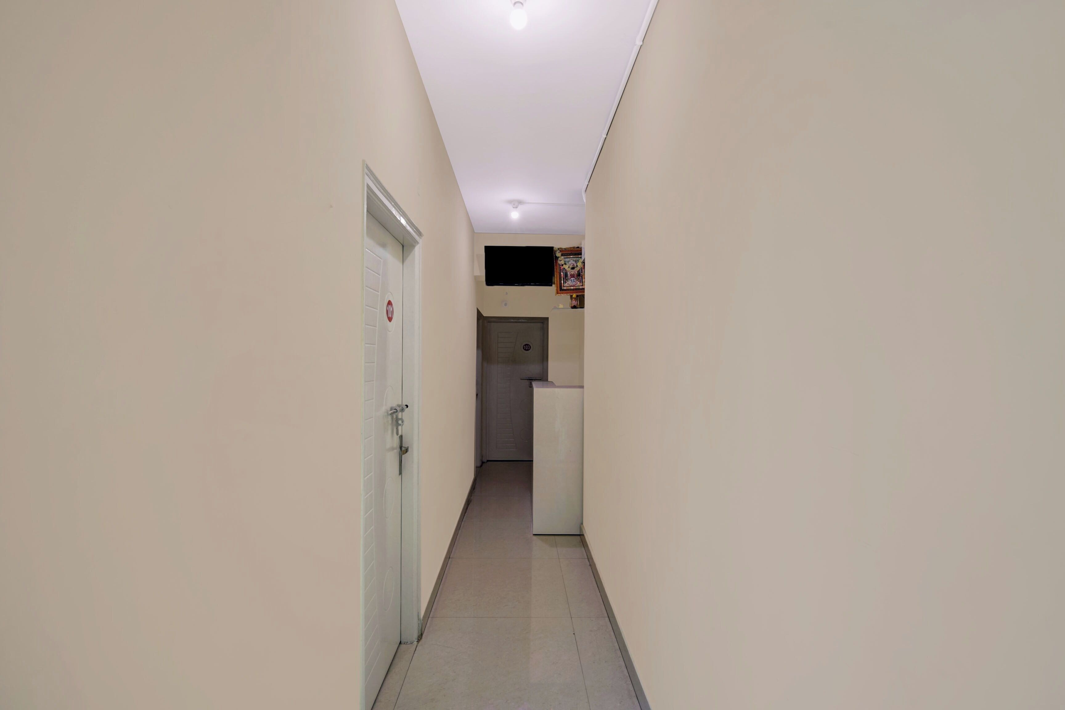 A narrow hallway with a door on the left and a small kitchenette area on the right.