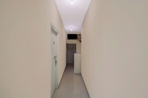 Un pasillo estrecho con una puerta a la izquierda y una pequeña zona de kitchenette a la derecha.