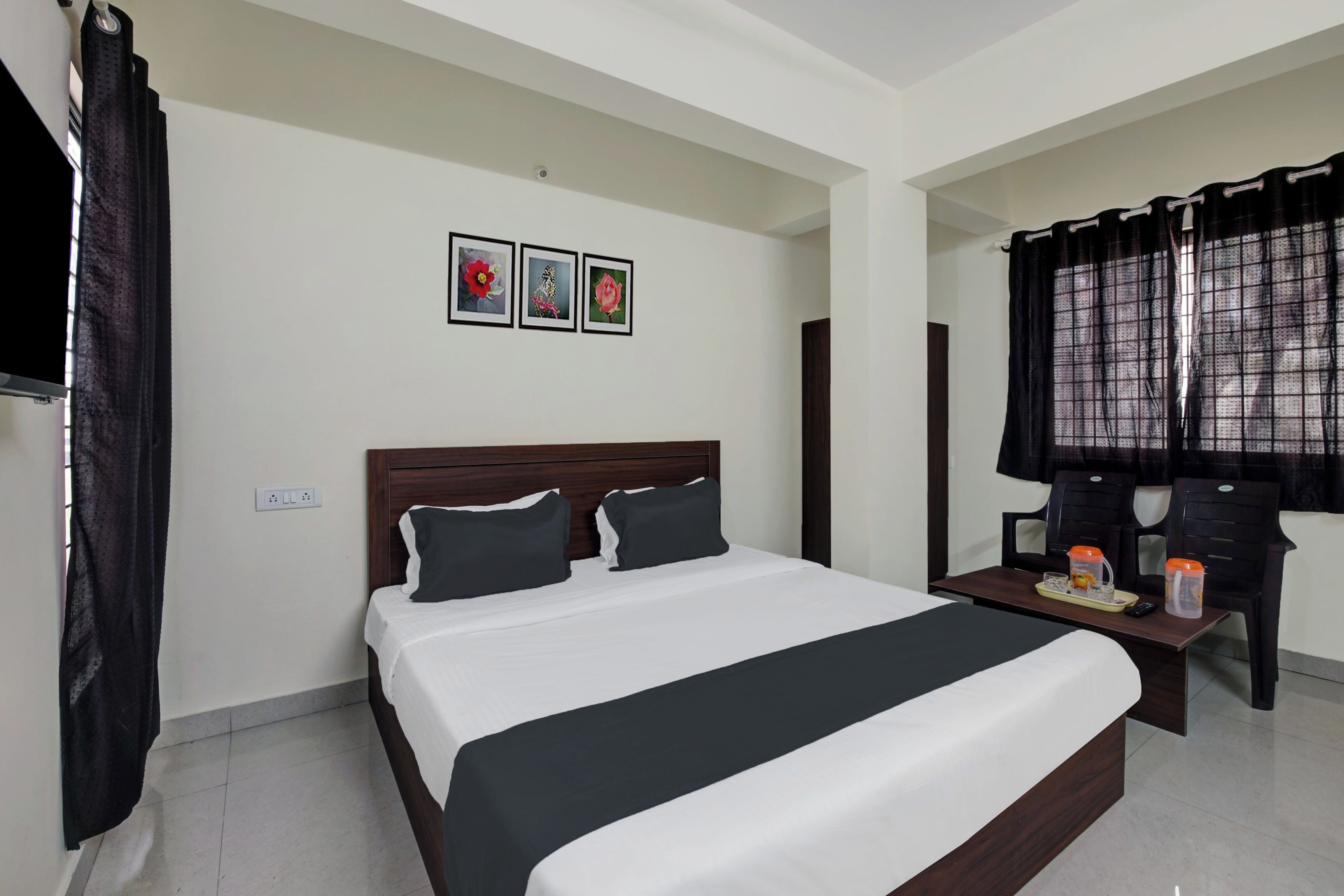 A hotel room with a large bed, a bedside table with a tray, a TV, and a window with curtains.