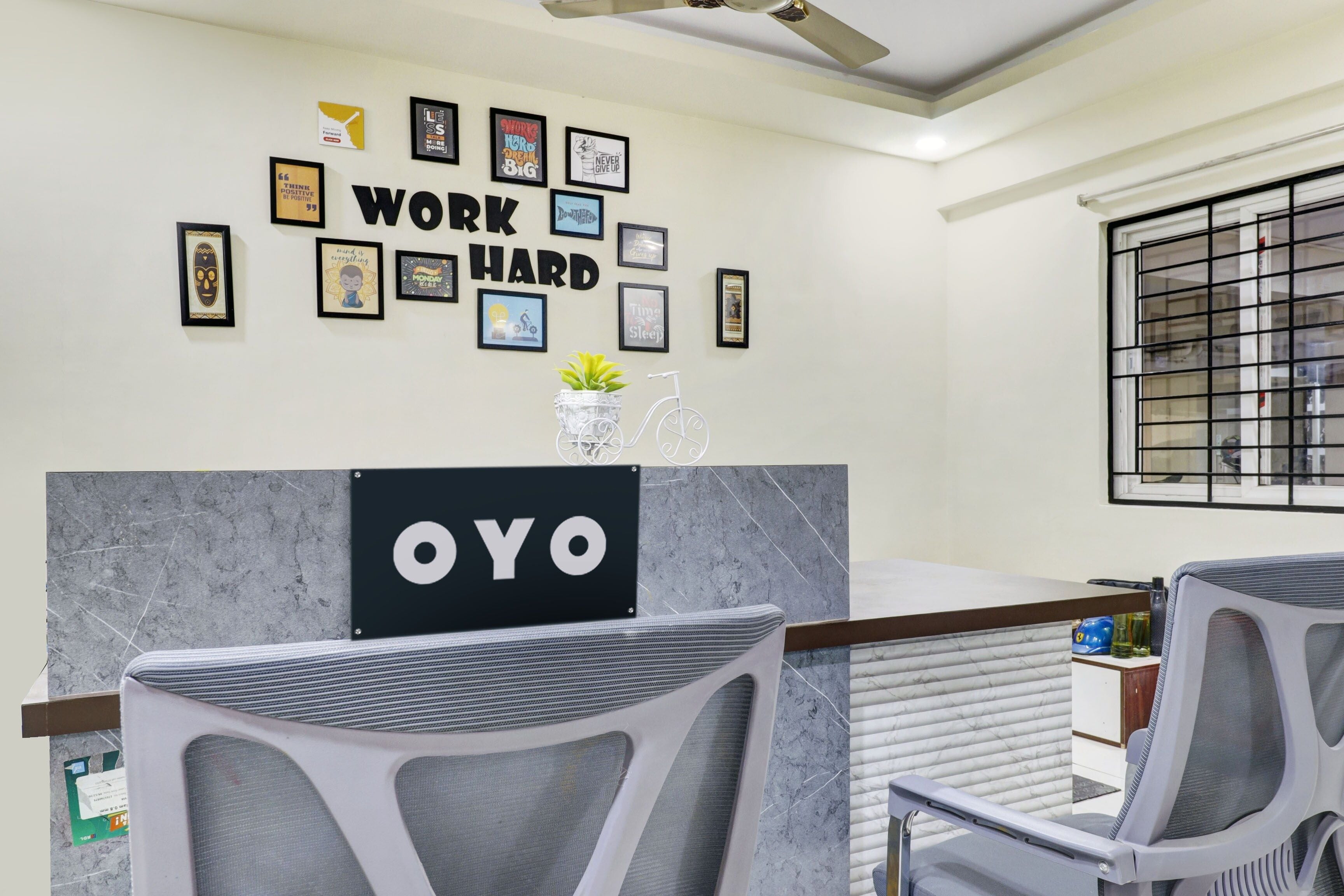 Una zona de recepción con mostrador de mármol, carteles motivacionales enmarcados y un letrero que dice 'OYO'.