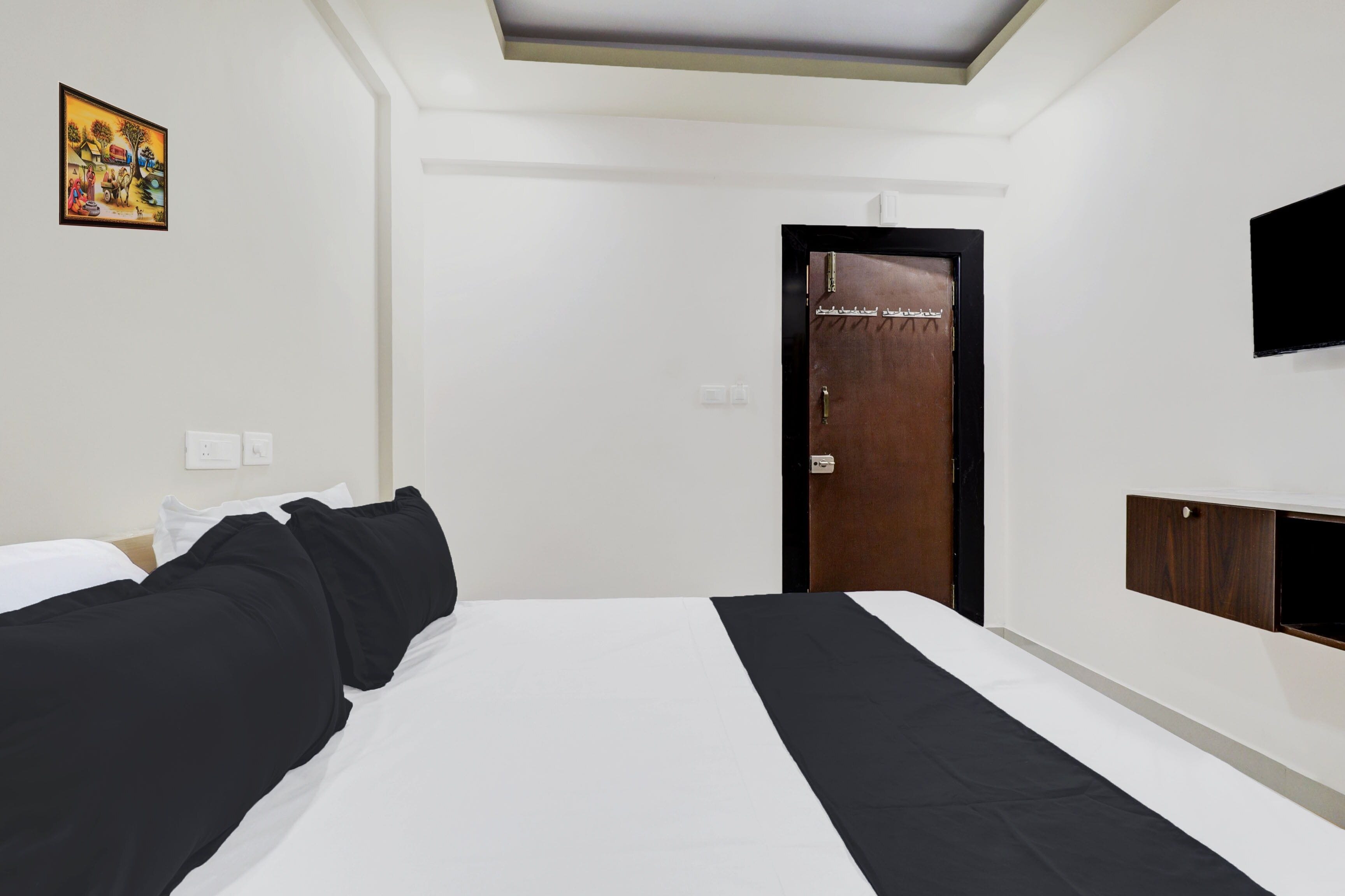 Una habitación de hotel con cama, armario, televisor y puerta con un cartel.