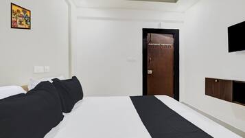 Una habitación de hotel con cama, armario, televisor y puerta con un cartel.