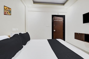 Ein Hotelzimmer mit einem Bett, einem Kleiderschrank, einem Fernseher und einer Tür mit einem Schild.