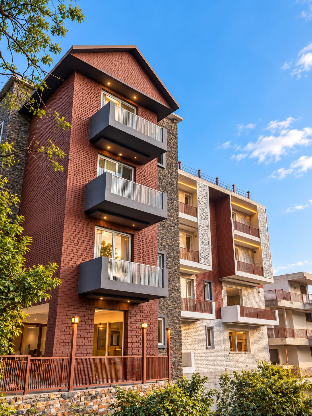 Un edificio residencial de varios pisos con balcones, fachada de piedra y cielo despejado.