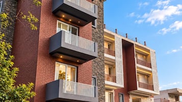 Un edificio residencial de varios pisos con balcones, fachada de piedra y cielo despejado.