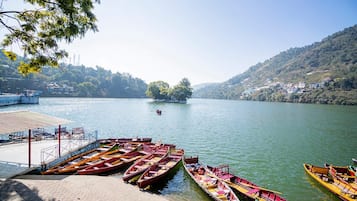 Un lago tranquilo con barcos amarrados en un muelle, rodeado de colinas y una pequeña isla con árboles.