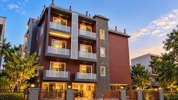 Un edificio residencial de varios pisos con balcones, fachada de piedra y entrada protegida por una reja.