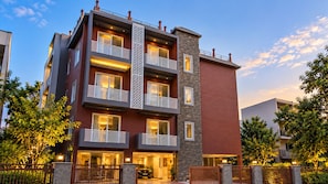 Edifício residencial com vários andares, varandas, fachada de pedra e entrada com portão.
