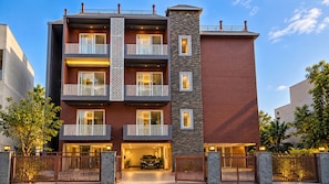 A multi-story hotel with balconies, a stone facade, and a gated entrance. - The Daiichi Grand (Bhimtal)