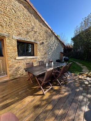 A stone building with a wooden deck and a table with chairs. - Holiday Home 'Gite Lo Pomier' with Wi-Fi and Air Conditioning (Boulazac Isle Manoire)