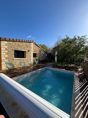Una piscina con un muro de piedra y una cubierta de madera.