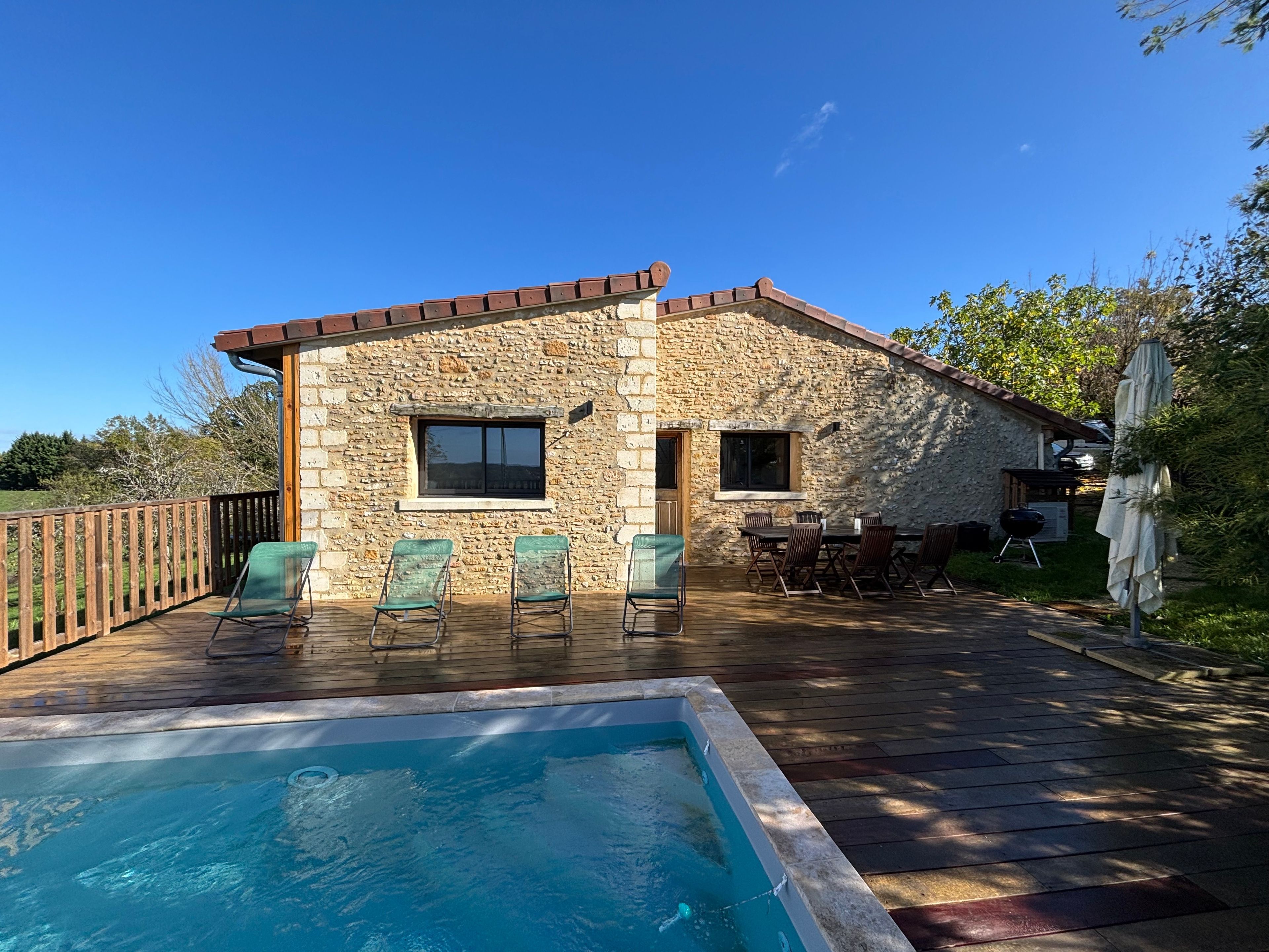 Una casa de piedra con piscina, mobiliario exterior y zona de barbacoa.