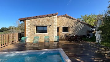 Una casa de piedra con piscina, mobiliario exterior y zona de barbacoa.