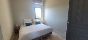 A bedroom with a bed, pillows, a nightstand, a window, and a door. - Holiday Home 'Gite Lo Pomier' with Wi-Fi and Air Conditioning (Boulazac Isle Manoire)