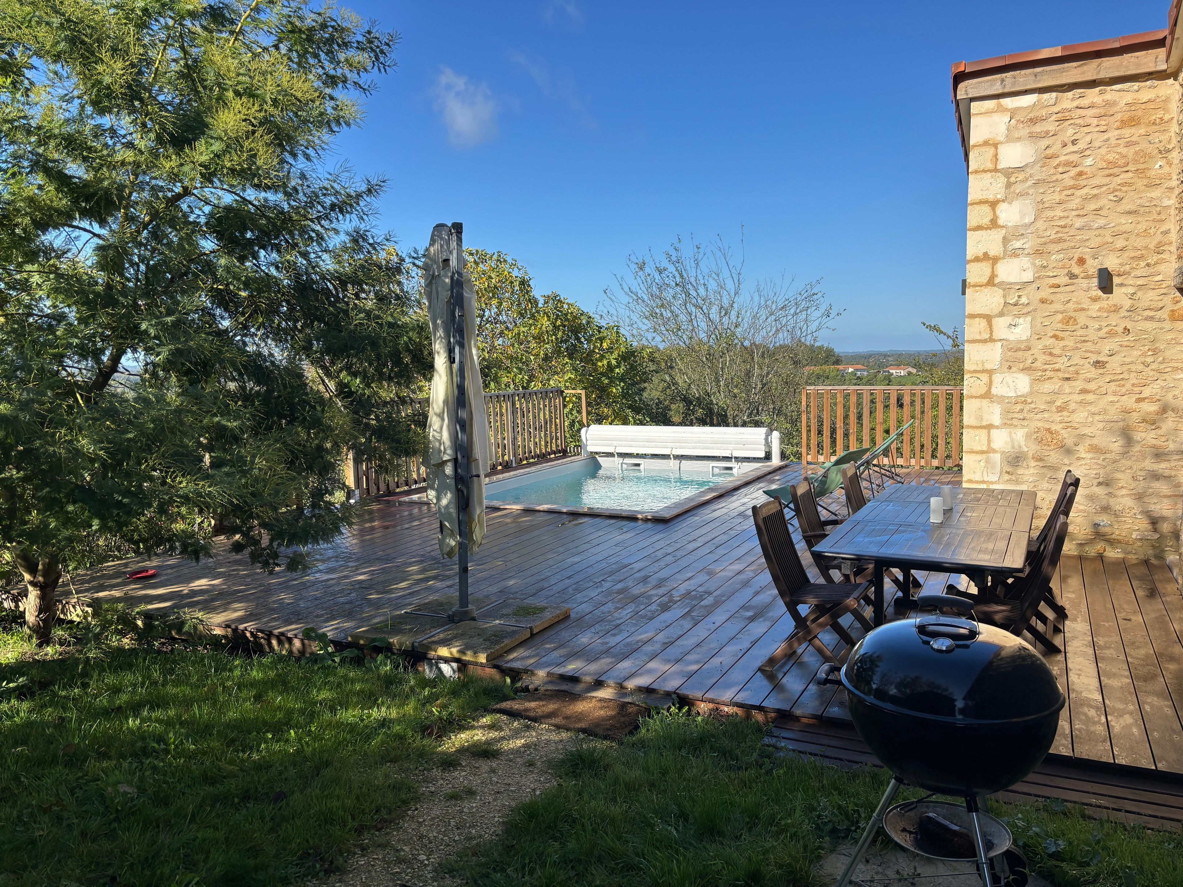 A backyard with a swimming pool, outdoor furniture, and a barbecue grill.