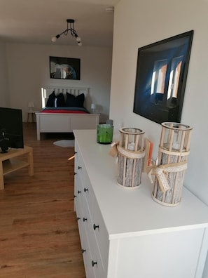 A modern living room with a white sofa, a television, and decorative lanterns on a white console table.