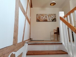 Eine Treppe mit Holzstufen und weißen Geländern, die zu einem Raum führt, in dem sich ein Blumenbild an der Wand befindet.