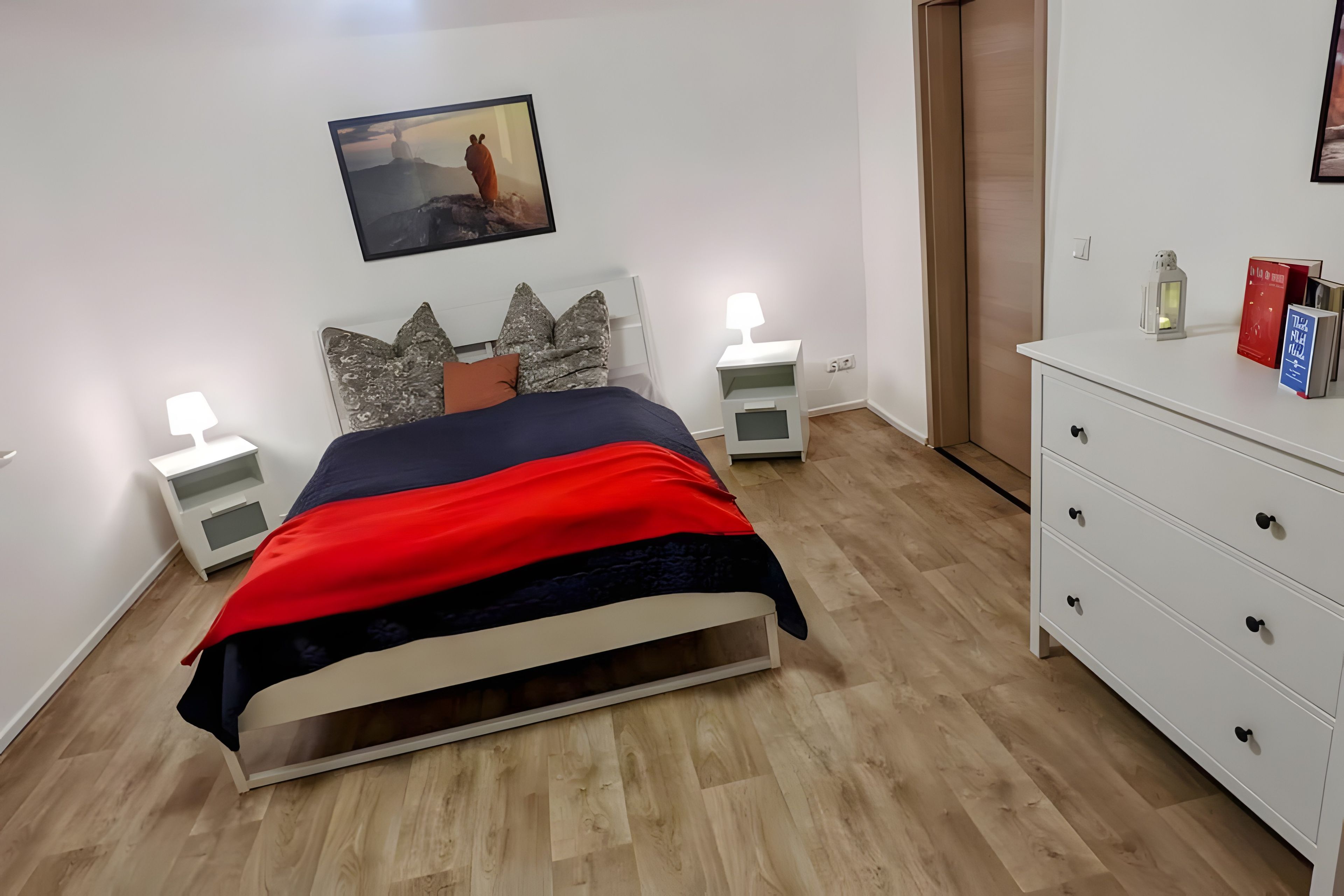 Ein Schlafzimmer mit Bett, Nachttischen, einem Schminktisch und einem Bild an der Wand.