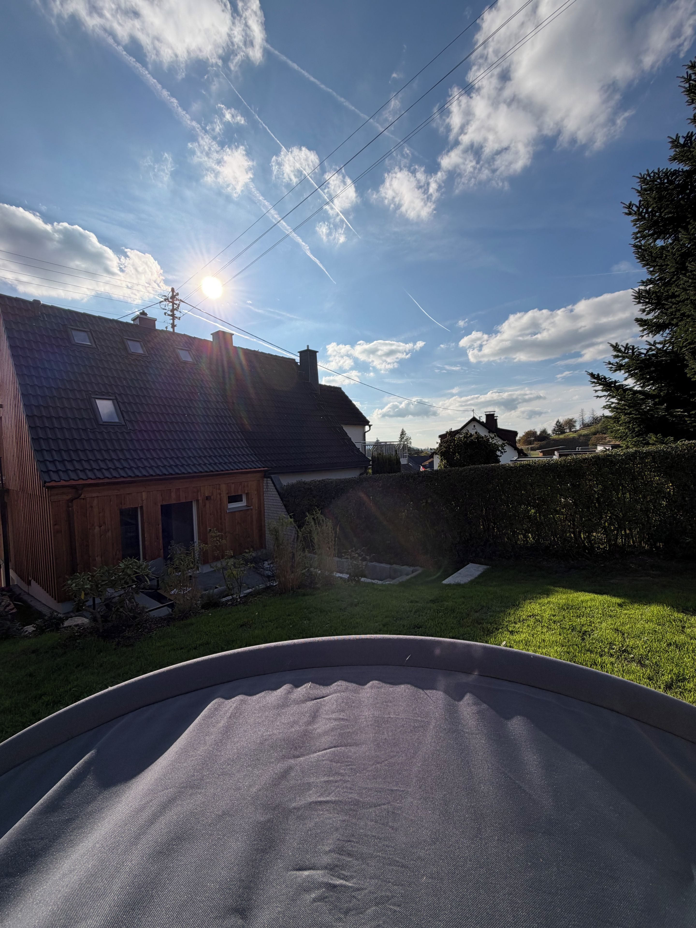 Ein Wohnhausgarten mit Pool, einem Holzhaus und blauem Himmel.