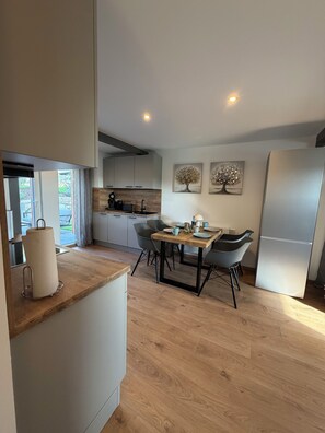 A modern kitchen with a dining area, wooden flooring, and a refrigerator. - New Listing (Schwarzenbach am Wald)