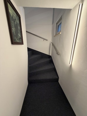 A stairway with a handrail, a picture on the wall, and a light fixture.