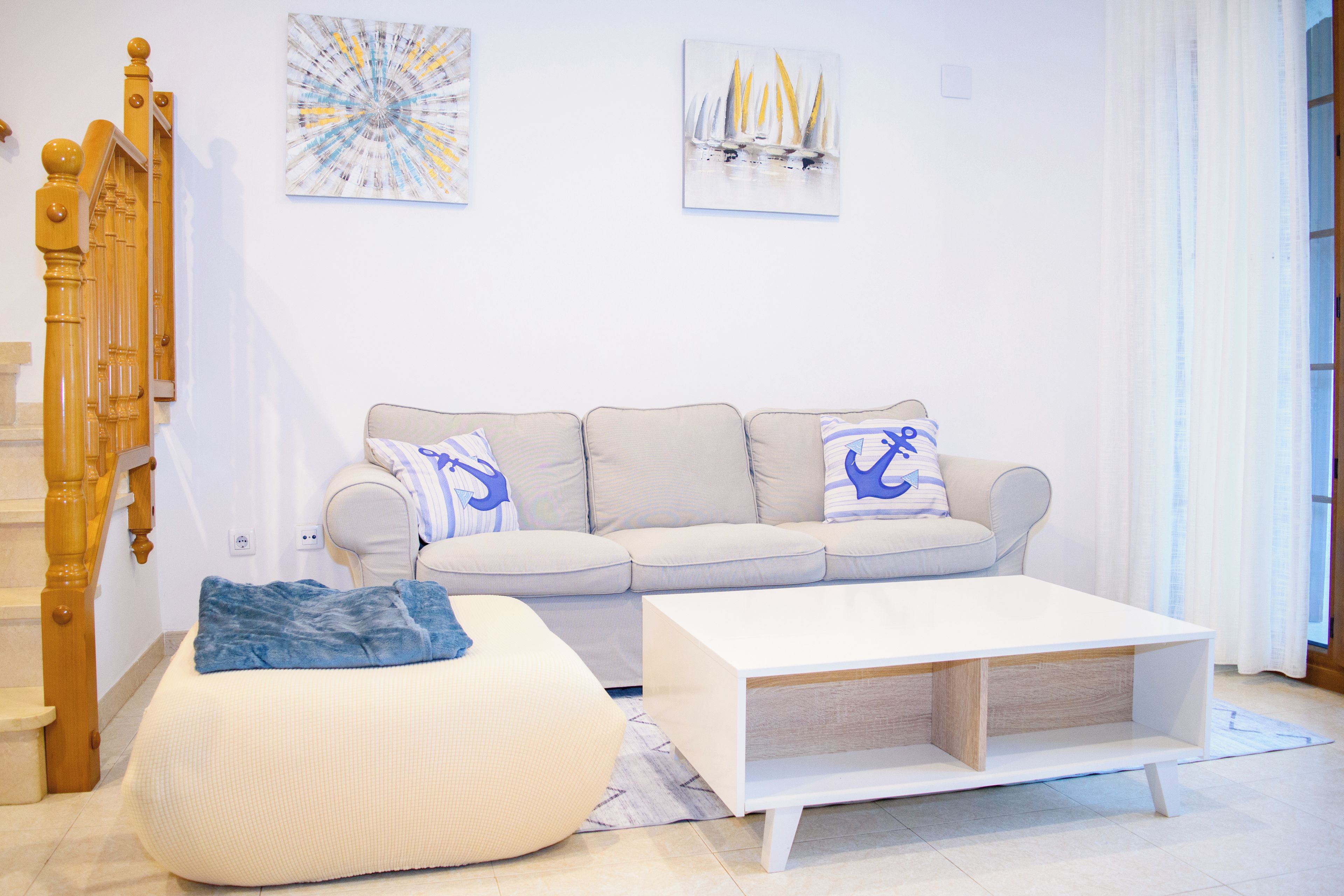 Ein Wohnzimmer mit Sofa, Hocker, Couchtisch und einer Treppe.