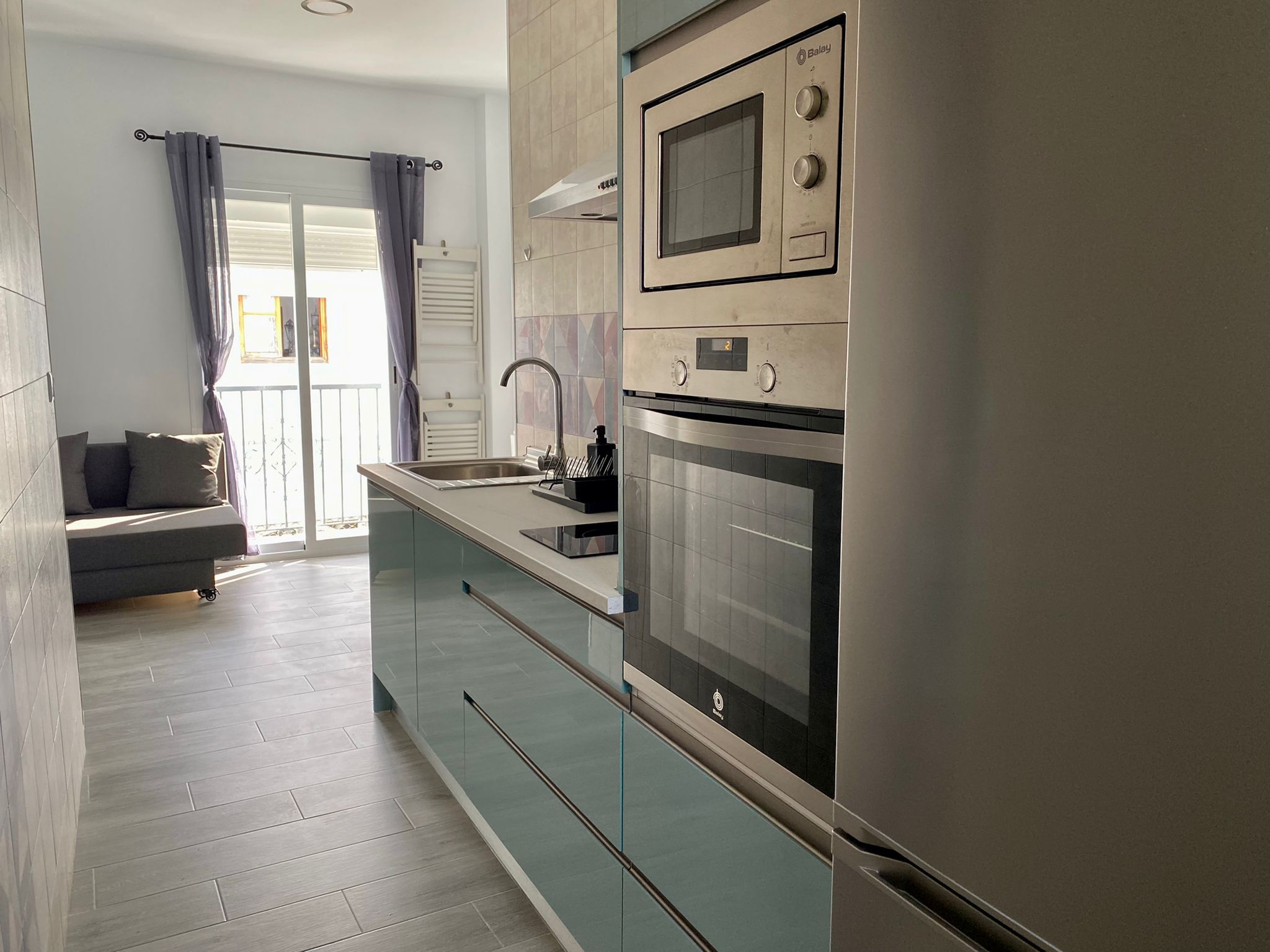A modern kitchen with a built-in oven, microwave, and a sink.