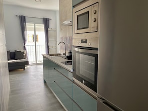 Una cocina moderna con horno empotrado, microondas y lavamanos.