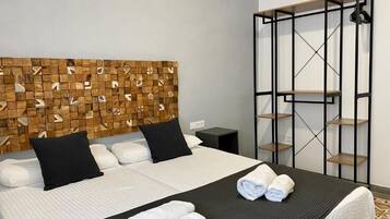 A hotel room with a bed, a headboard with a geometric pattern, a black metal shelf unit, and a patterned floor.