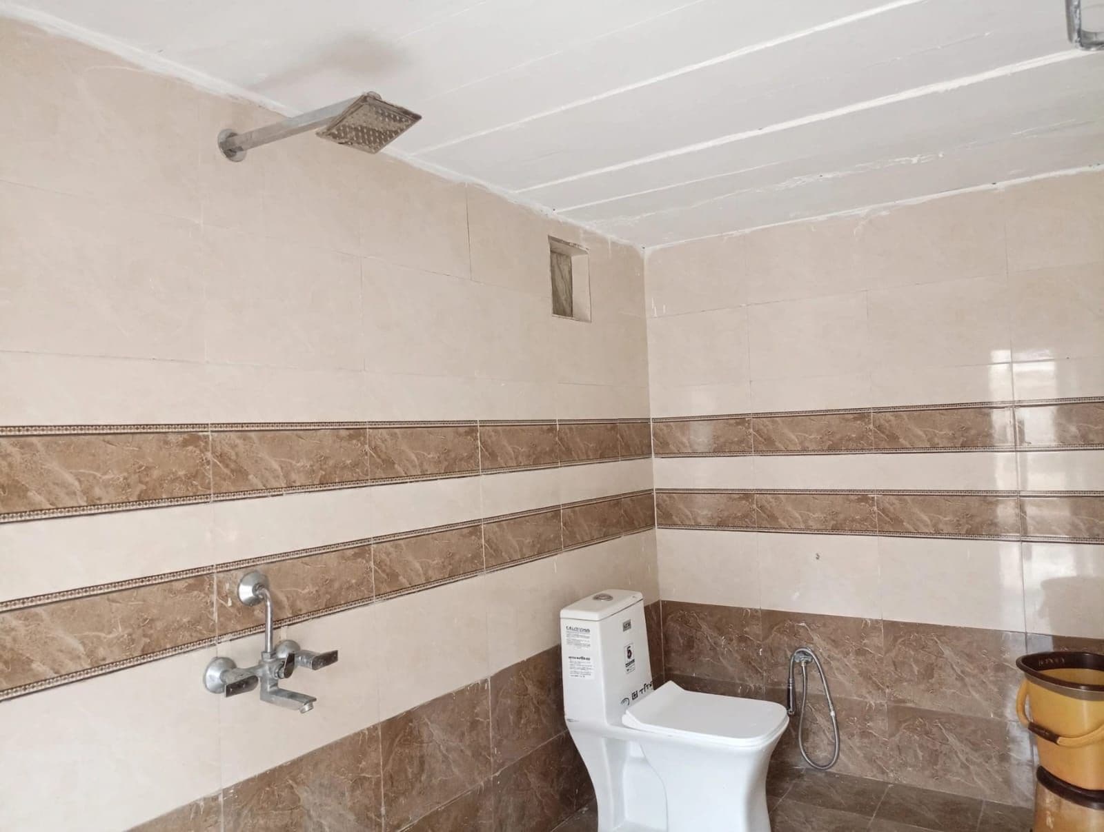 A bathroom with a shower, toilet, and hand dryer.