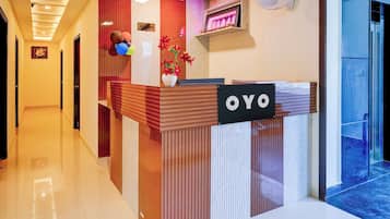 A reception desk with a 'YOYO' sign, a reception area with a camera, and a wall-mounted fan.