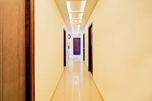 Ein Hotelgang mit Fliesenboden, Holztüren und einer Decke mit eingelassener Beleuchtung.
