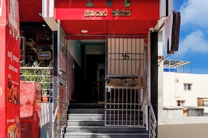 Ein rotes Gebäudeeingang mit einem Metallgitter und einer Treppe, die nach innen führt.