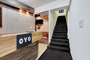 Uma mesa de recepção com acabamento em madeira e uma placa com a inscrição 'OYO'.