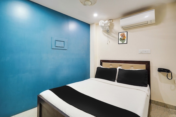 Un dormitorio con cama, aire acondicionado instalado en la pared, teléfono y un interruptor de luz.