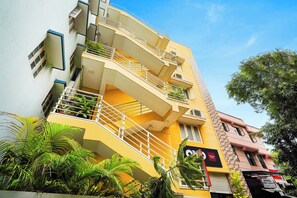 Un edificio de varios pisos con una escalera curva, balcones y plantas en macetas.