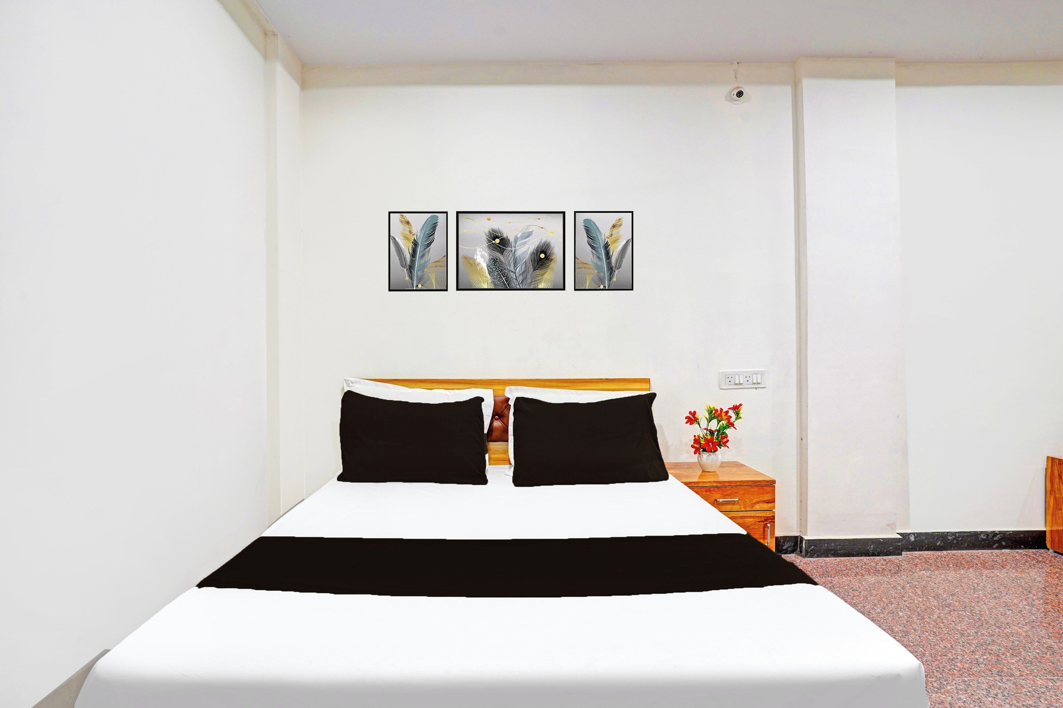 Una habitación de hotel con una cama, una mesita de noche y un enchufe en la pared.