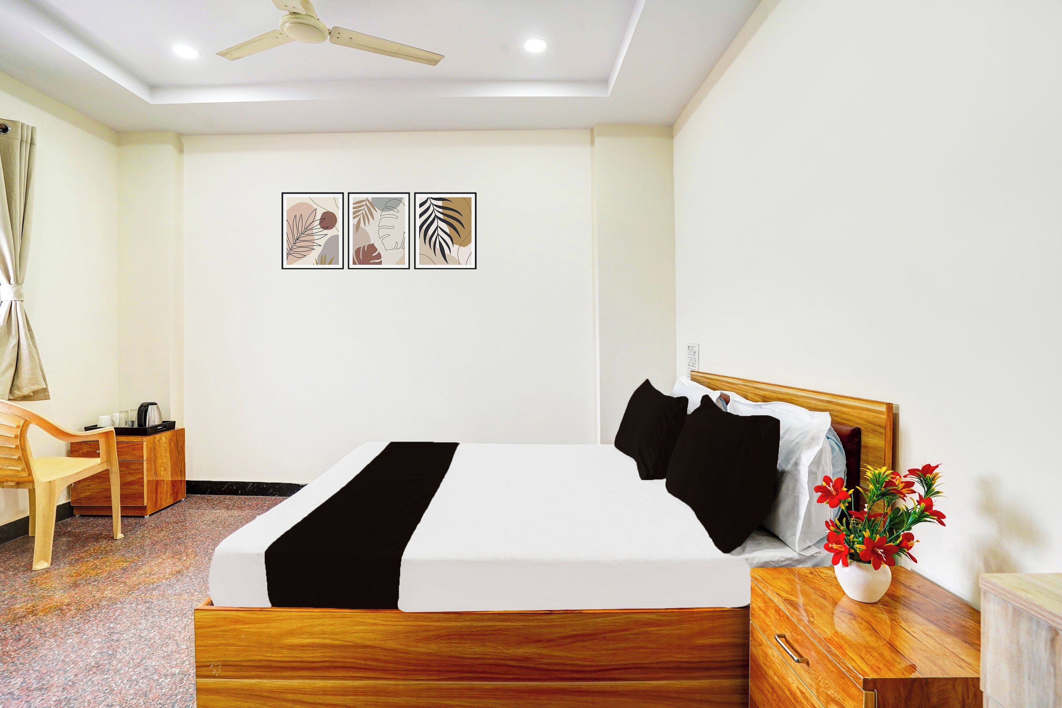 Habitación de hotel con una cama, escritorio, silla, ventilador de techo y decoración en la pared.