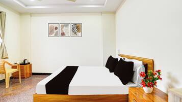 Habitación de hotel con una cama, escritorio, silla, ventilador de techo y decoración en la pared.
