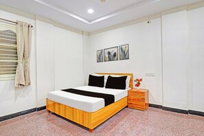 Un dormitorio con una cama, una mesita de noche y un estante en la pared.
