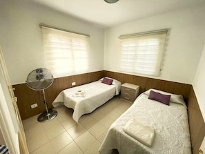 A room with two beds, a fan, and a window with blinds. - 🌟 CASA MIMOSA Two Bedroom Apartment Central Caleta Pool Private Roof Terrace 🌟 (Castillo Caleta de Fuste)